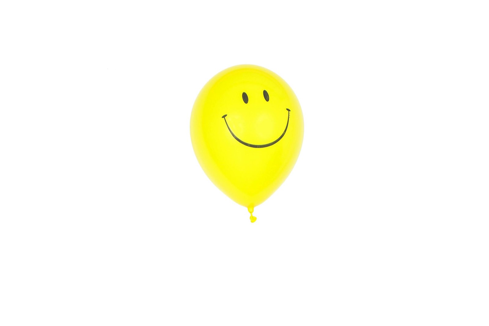 Bright yellow balloon with a smiley face floating against a white backdrop.